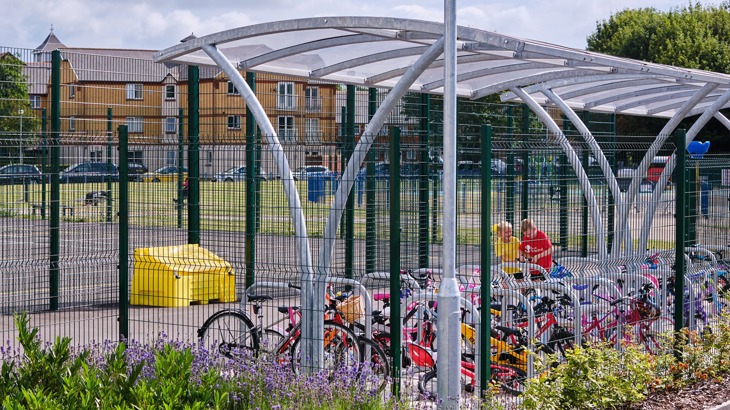 Secure cycle storage in school playground with two children locking up their bikes