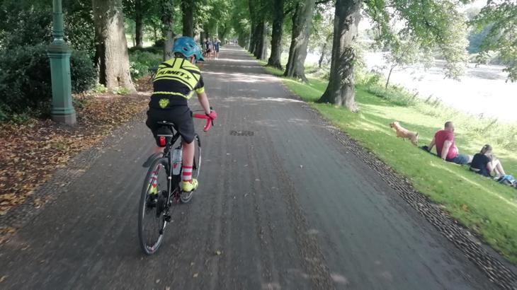 Boy cycling along traffic-free route lined with trees