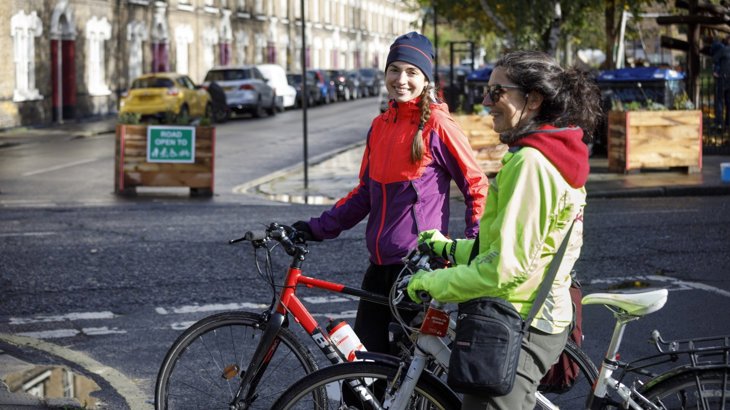 two women sitting on their bikes having a conversation in the street in a Low Traffic Neighbourhood in London