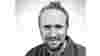Black and white headshot of Walk Wheel Cycle Trust project officer, James Wheale, looking to camera smiling.