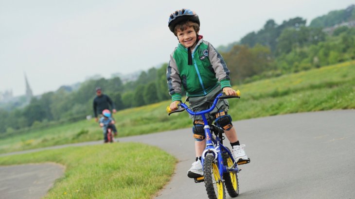 Child cycling alongside river Exe in Exeter