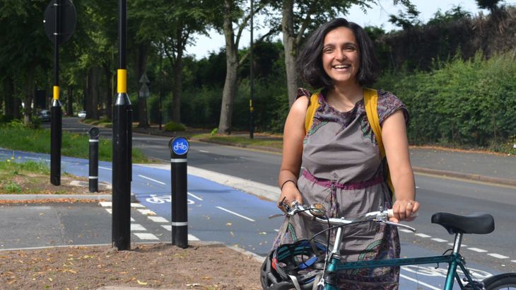 Our West Midlands partnerships manager, Ridhi Kalaria standing with her bike next to a segregated cycle path in the centre of Birmingham.