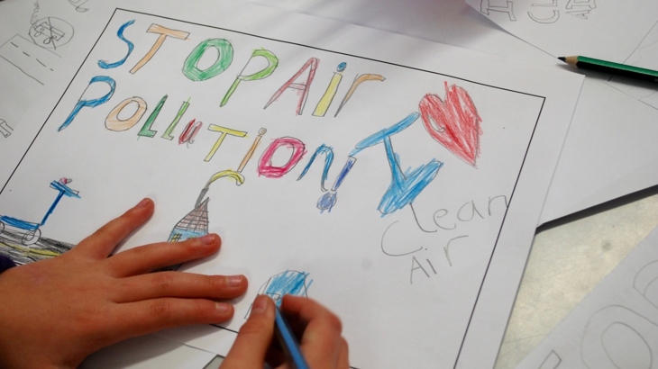 A poster saying "stop air pollution" being coloured in