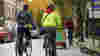 Two people on bikes wearing winter coats cycle in a low traffic neighbourhood in London.