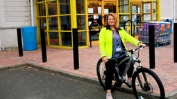 Woman wearing hi-vis sitting on new bike outside a bike shop
