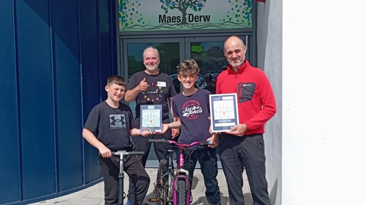 Walk Wheel Cycle Trust staff member stands posing for a photo with staff and pupils from Maes Derw pupil referral unit after they achieved their Silver Active Travel School Award.